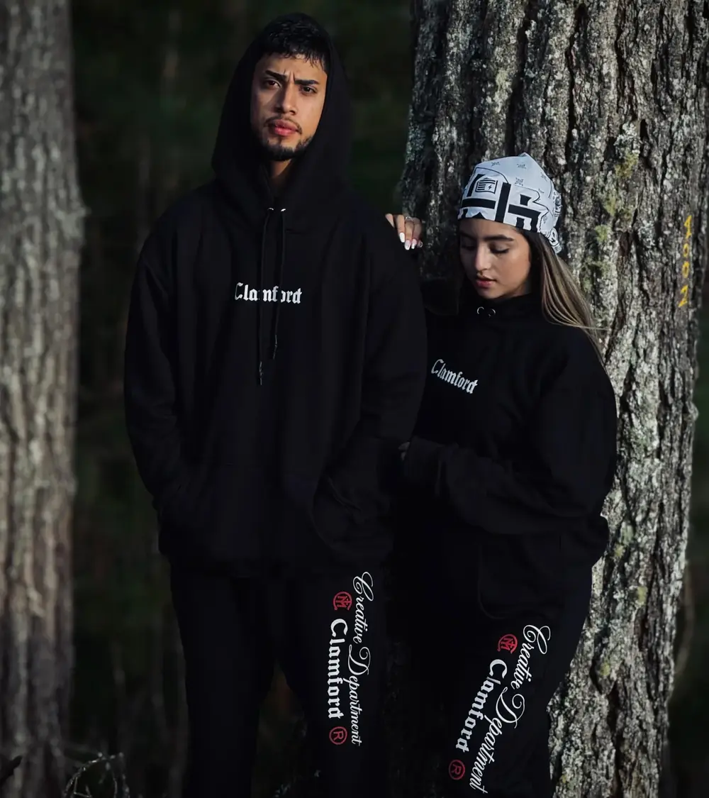 Pareja con hoodie y sudadera negra Clamford en un bosque